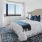 a bed with a white comforter in front of a large window